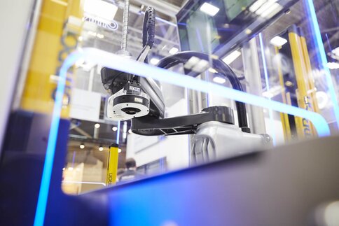 Industrial robot arm in a glass box at an exhibition stand.