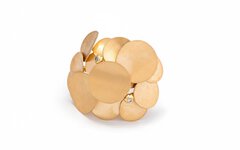 A close-up view of a delicate gold piece of jewelry consisting of gold plates attached to each other with two gemstones.