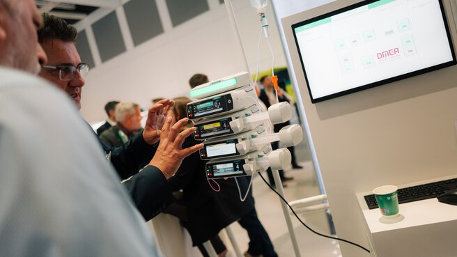 Visitor examining a medical infusion or pump system with monitor at a DMEA booth