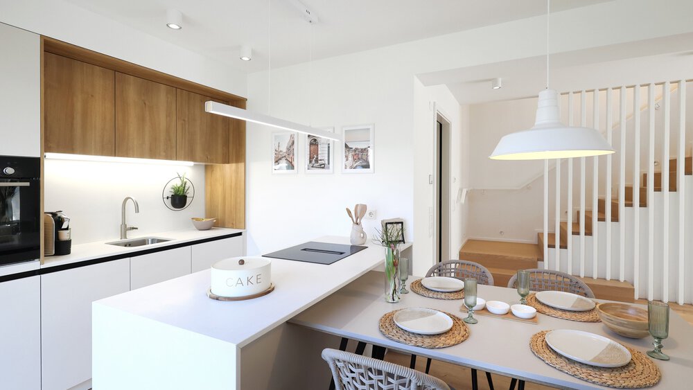 Moderner Küchen- und Essbereich mit weißem und hölzernem Dekor, gedecktem Tisch und Treppe im Hintergrund.