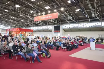 Interested visitors attentively follow a lecture on the travel stage at the f.re.e 2025