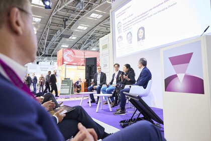 four people give a lecture on a stage while the audience watches