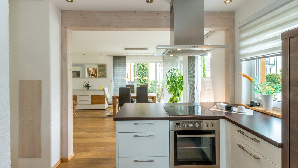 Moderne Küche mit Geräten aus Edelstahl, Arbeitsplatten aus Holz und Blick in einen hellen Essbereich.