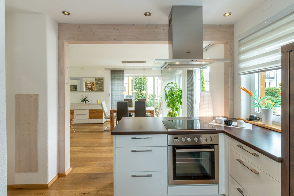 Moderne Küche mit Geräten aus Edelstahl, Arbeitsplatten aus Holz und Blick in einen hellen Essbereich.