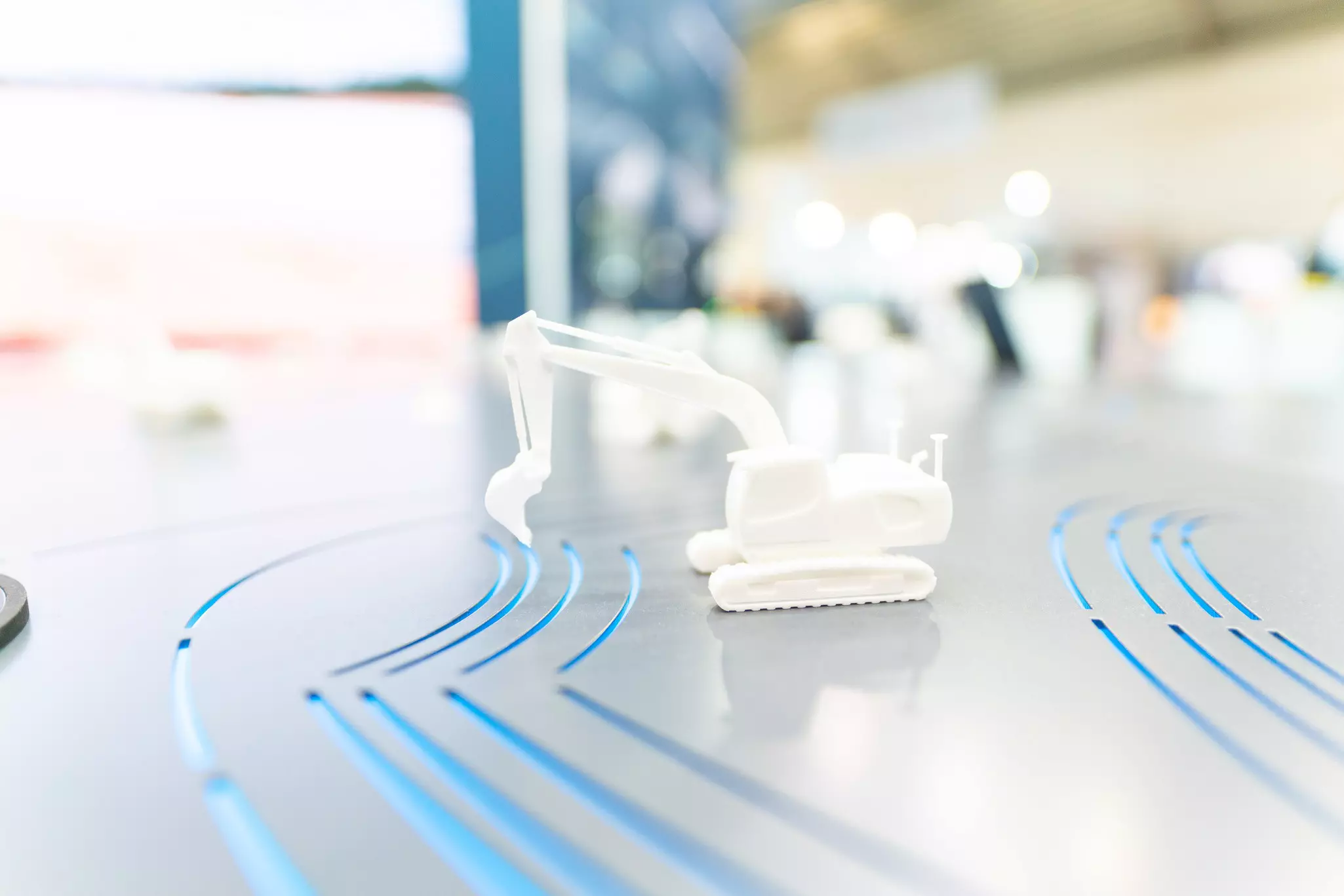 White miniature excavator on metal surface on the Hexagon stand at bauma 2022