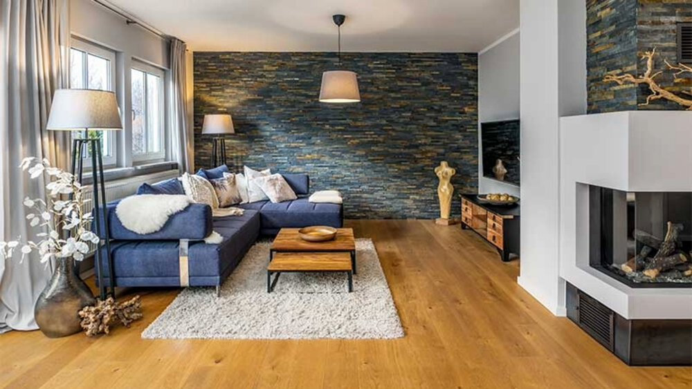 Ein gemütliches Wohnzimmer mit dunkelblauem Sofa, hölzernem Couchtisch, Kamin und modernem Dekor.