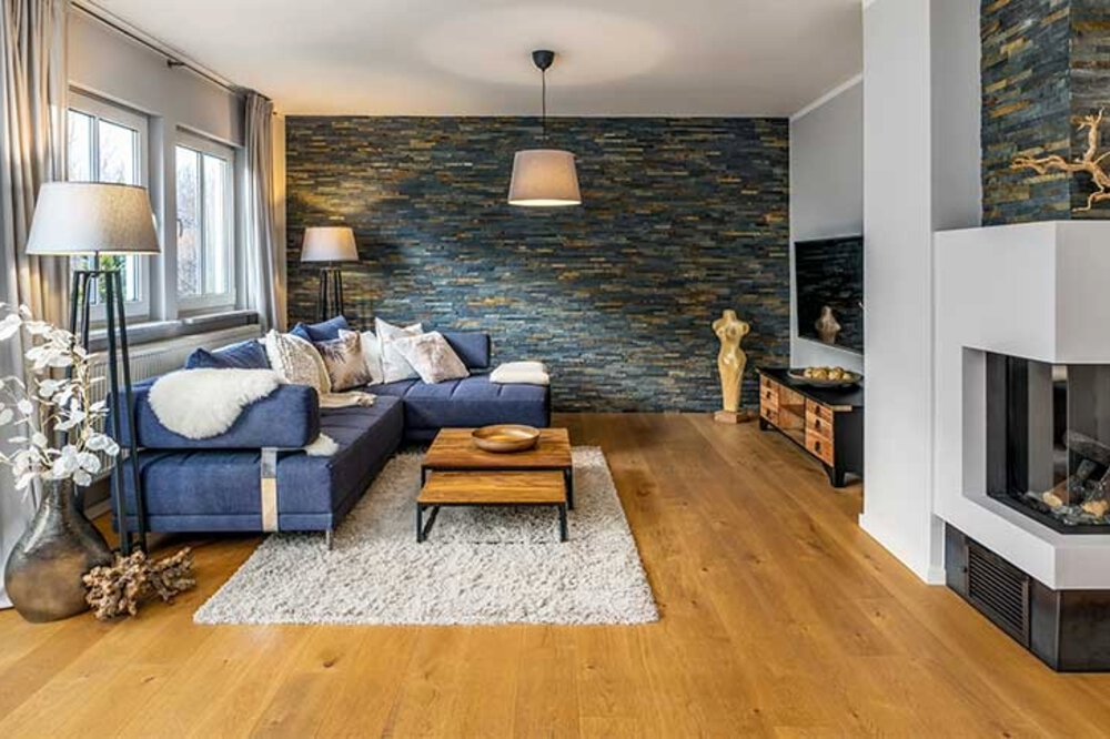 Ein gemütliches Wohnzimmer mit dunkelblauem Sofa, hölzernem Couchtisch, Kamin und modernem Dekor.