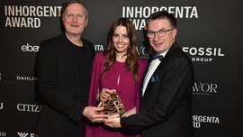 Drei strahlende Menschen mit der Trophäe für die Kategorie Next Generation Retail auf der AWARD-Gala vor einer Logowand.