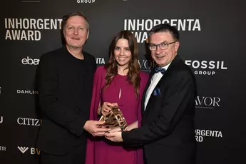 Drei strahlende Menschen mit der Trophäe für die Kategorie Next Generation Retail auf der AWARD-Gala vor einer Logowand.