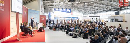 Fünf Personen auf einer Bühne vor einem großen Publikum während der transport logistic in Halle B2 der Messe München.