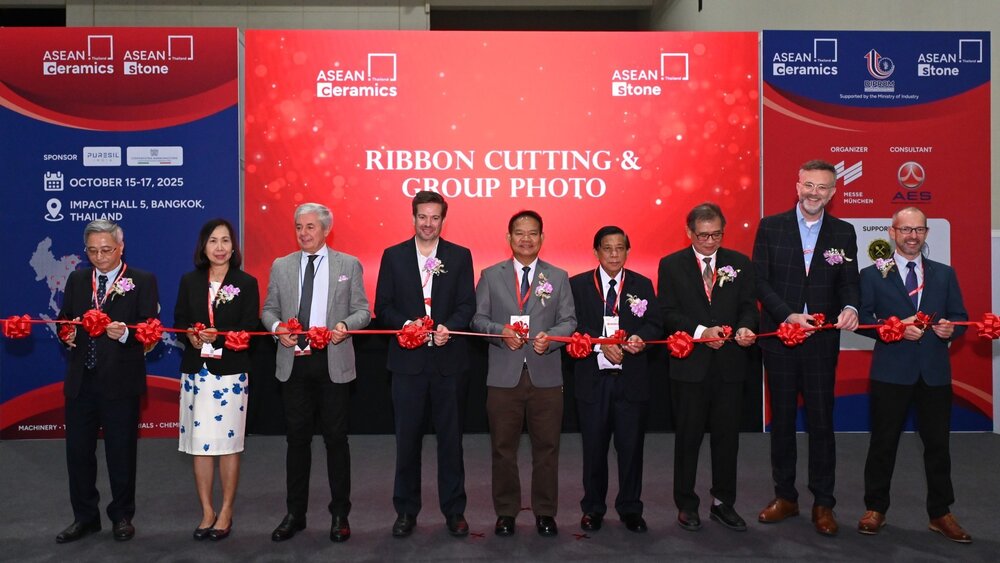 Nine people stand side by side with scissors at a long red ribbon, posing for the opening of Asean ceramics.