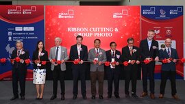 Nine people stand side by side with scissors at a long red ribbon, posing for the opening of Asean ceramics.