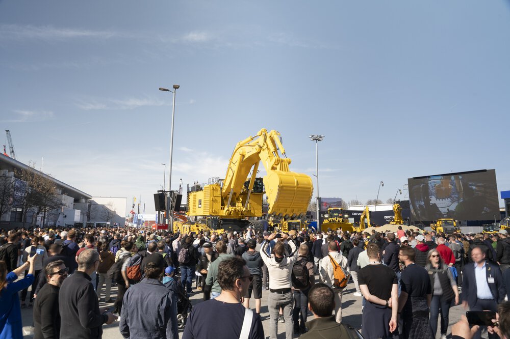 Bei einer Veranstaltung unter freiem Himmel versammelt sich eine große Menschenmenge um massive gelbe Baumaschinen.