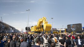 Bei einer Veranstaltung unter freiem Himmel versammelt sich eine große Menschenmenge um massive gelbe Baumaschinen.