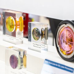 Various colorful optical linens cast in acrylic, displayed at a brightly lit booth.