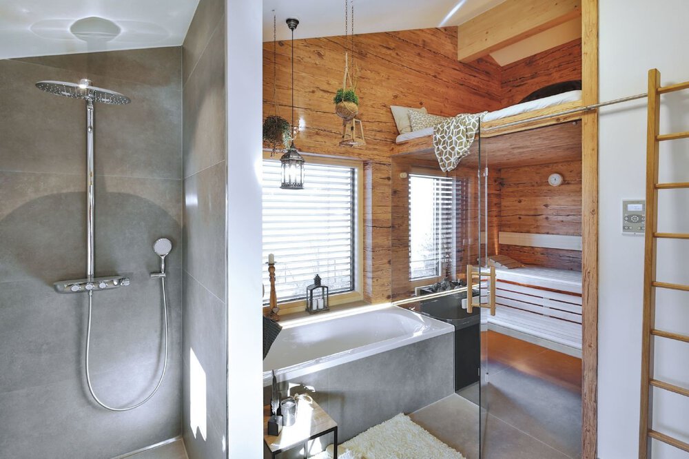 Modernes Badezimmer mit Dusche, weißem Waschbecken und Holzregalen. Helle Holzböden und -wände sorgen für eine warme Atmosphäre.