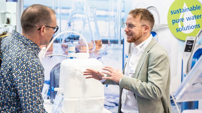 Two trade show attendees discuss sustainable solutions for clean water.