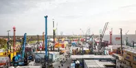 Wide-angle view of the outdoor areas with various cranes and construction machinery under a cloudy sky.