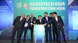 Sieben Männer in Anzügen stehen um ein Rednerpult herum und haben alle eine Hand daraufgelegt. Hinter ihnen steht „GLASSTECH ASIA FENESTRATION ASIA“.