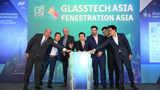 Sieben Männer in Anzügen stehen auf der Bühne und legen ihre Hände auf das Podium. Hinter ihnen ist ein großer 