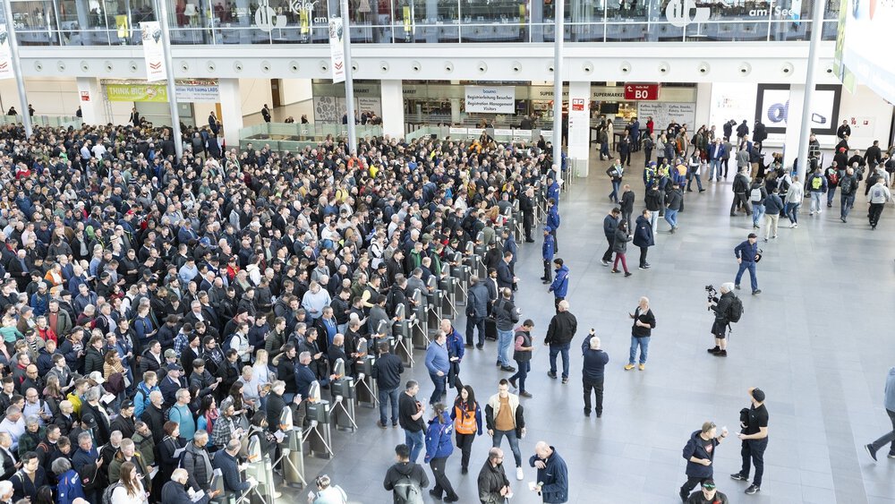 A large crowd gathered in a spacious indoor area, some people were filming and taking photos.