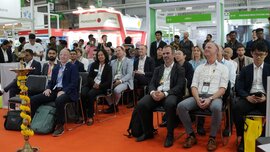 A cheerful audience sits on chairs in the 