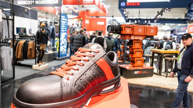 Close-up of a black and orange shoe at a trade fair stand for workwear at BAU.
