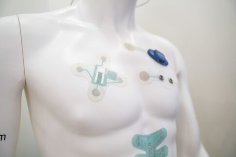 A torso of a mannequin with various sensors and electronic patches glued to its chest and shoulders.
