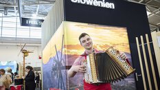 Traditionelle Musikdarbietung eines Ziehharmonika-Spielers am Slowenien-Stand einer Freizeitmesse.