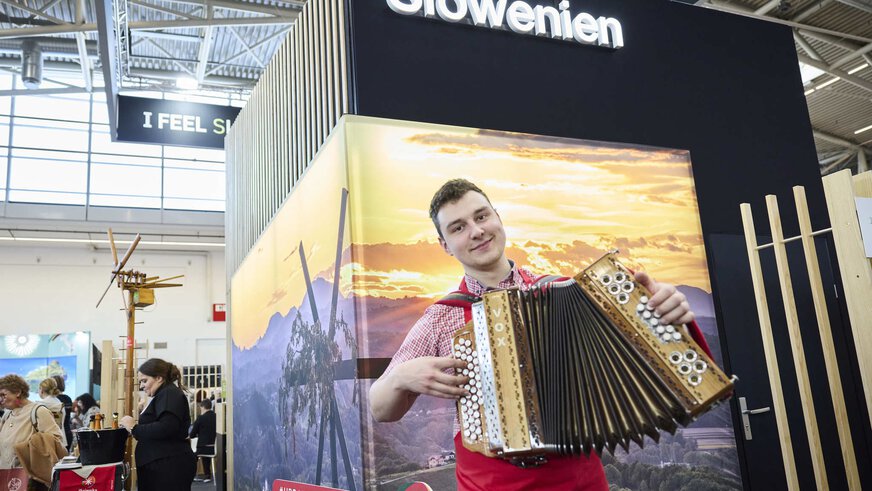 Traditionelle Musikdarbietung eines Ziehharmonika-Spielers am Slowenien-Stand einer Freizeitmesse.