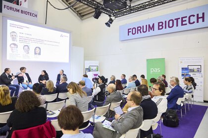 Four people lead a panel discussion at Forum Biotech, with the audience sitting in front of them