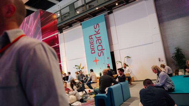 Lounge and networking area at DMEA sparks Careers with large banner and seated attendees