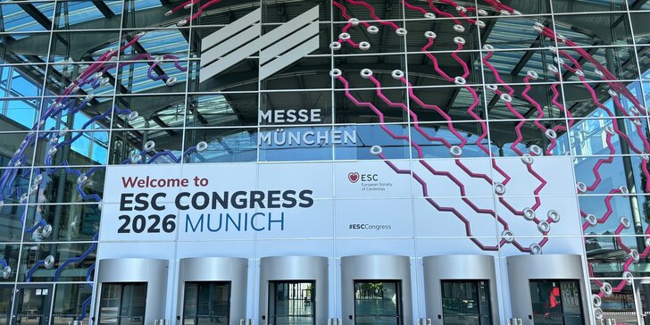 Blick auf eine Eingangshalle der Messe München zum ESC Congress 2026 mit einer passend dekorierten Glasfassade mit sechs Drehtüren darin.