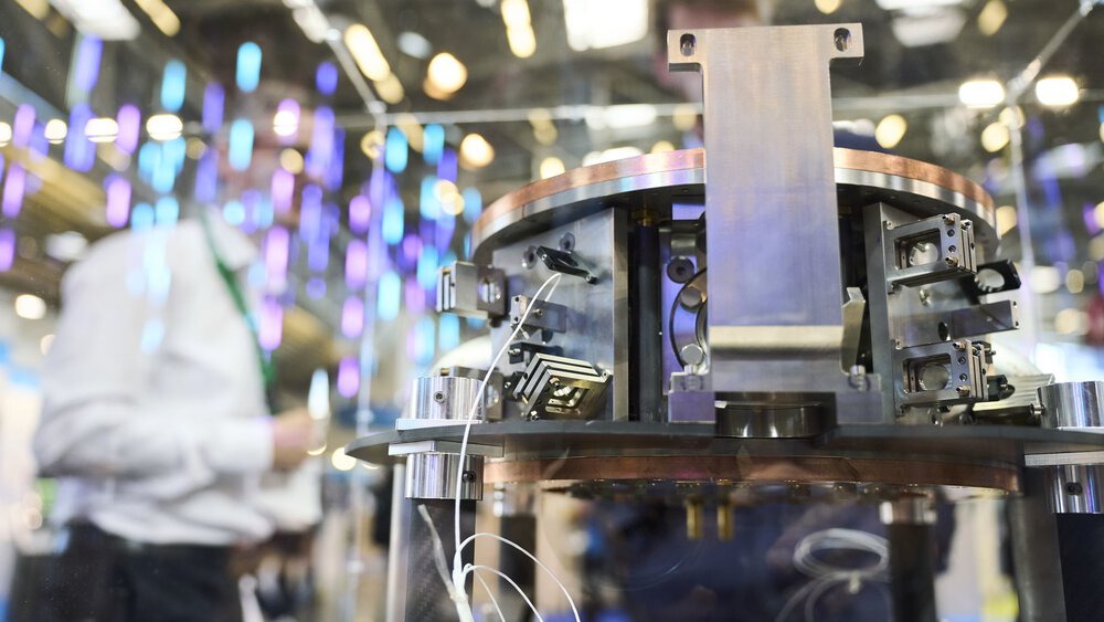 Close-up of scientific equipment with wires, displayed at a technology exhibition with people in the background.