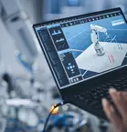 Hand of person using laptop to program robotic arm using advanced technology such as AI