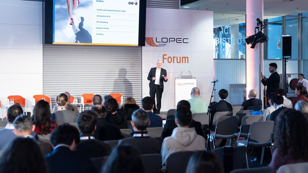 Speaker presenting OEA outline on flexible and printed electronics at LOPEC Forum