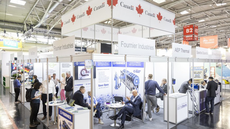 Auf dem Bild ist ein großer Gemeinschaftsstand von Kanada zu sehen. Der Stand befindet sich in Halle B2 der Messe München auf der IFAT Munich. Man erkennt Firmennamen wie „Fournier Industries und AEP Thermal. Im Hintergrund finden angeregt Unterhaltungen zwischen den Ausstellern und interessierten Besuchern statt.
