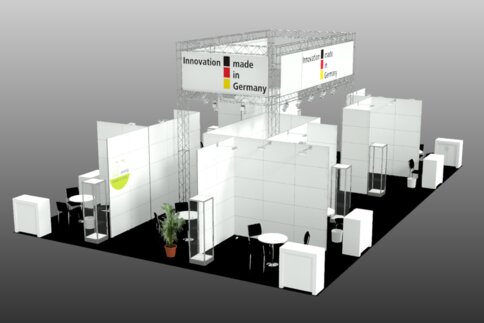 Messestand „Innovation made in Germany“ mit modularen weißen Wänden, Möbeln und Vitrinen in einer Messehalle.