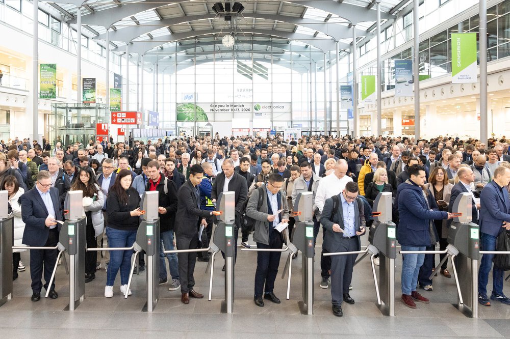 Eine große Menschenmenge strömt durch die Drehkreuze am Eingang West der Messe München zur electronica 2024