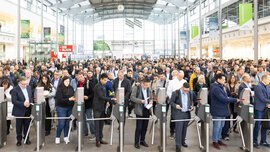 Eine große Menschenmenge strömt durch die Drehkreuze am Eingang West der Messe München zur electronica 2024