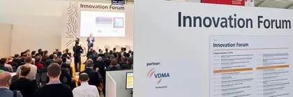A large audience in the ‘Innovation Forum’ at productronica listens to a man on stage. In the foreground is an information board with sponsors and event details.