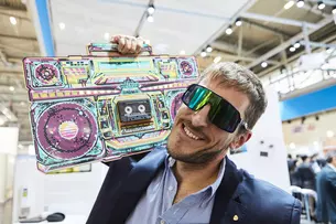 Man with sunglasses carries a colorful ghetto blaster on his shoulder