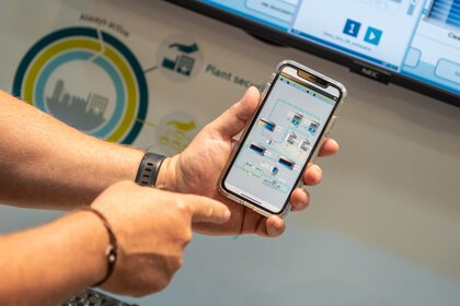 Person holding a smartphone displaying a flowchart for the exhibit visible in the background.