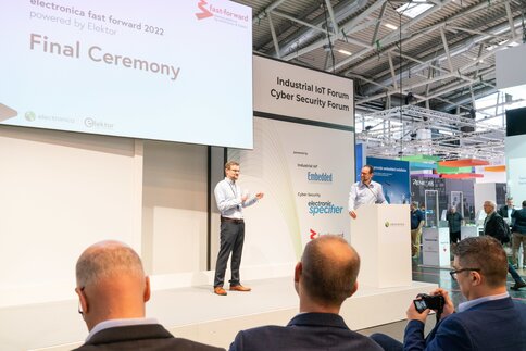 Two speakers stand on stage at the closing ceremony of electronica fast forward 2022.
