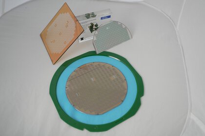 Various silicon wafers and substrates with microchips on a white surface, presented by the Institute for Microsystems Technology