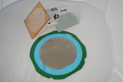Various silicon wafers and substrates with microchips on a white surface, presented by the Institute for Microsystems Technology