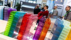 Zwei Reihen durchsichtige bunte Fassadensteckelemente aus Polycarbonat werden zu Anschauungszwecken an einem Stand auf der BAU ausgestellt.
