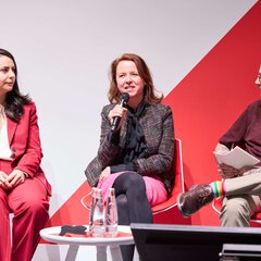 Panel discussion with three participants, one person speaking into a microphone.