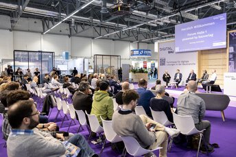 A stage with a panel discussion involving several people and a full auditorium.