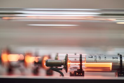 Side close-up of an active laser under a glass cover. Other lasers can be seen blurred in the background.